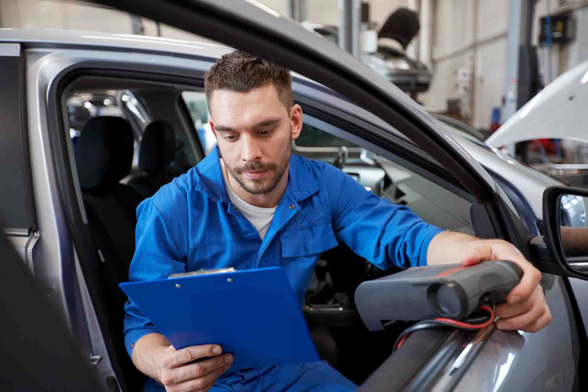 mechanic man with diagnostic scanner at car shop