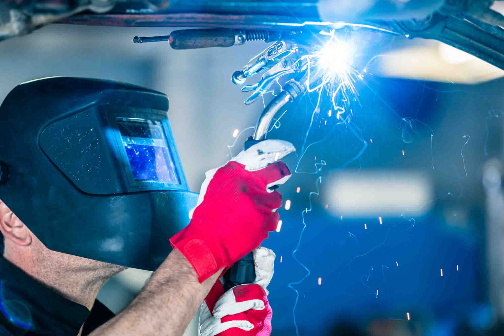 Technician Welding vehicle for repair - Auto Body Repair - Action Colors 