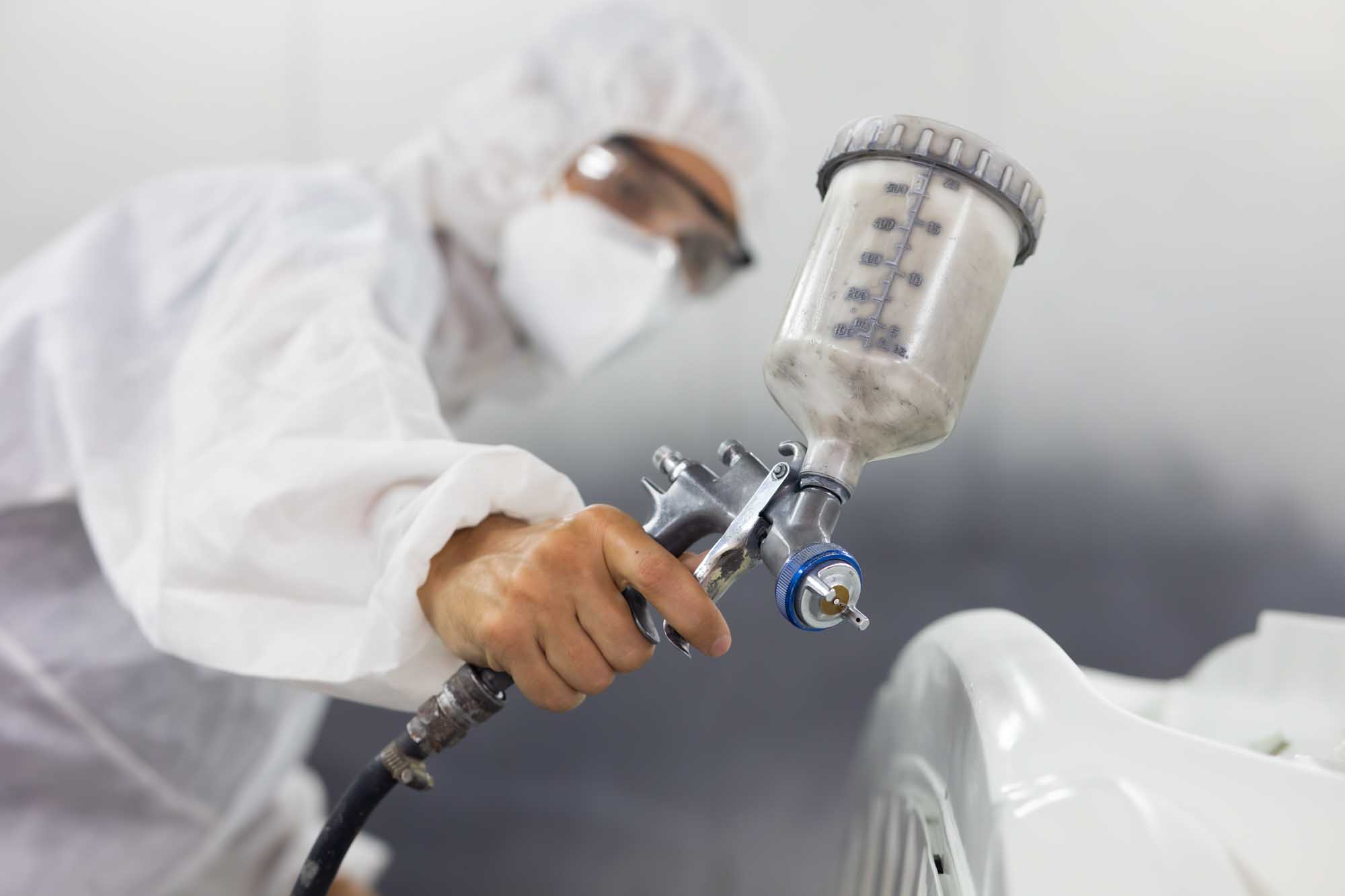 Close up shot of painter in booth spraying white bumper – our repair process – action colors tallahassee Close up shot of painter in booth spraying white bumper - our repair process - action colors tallahassee