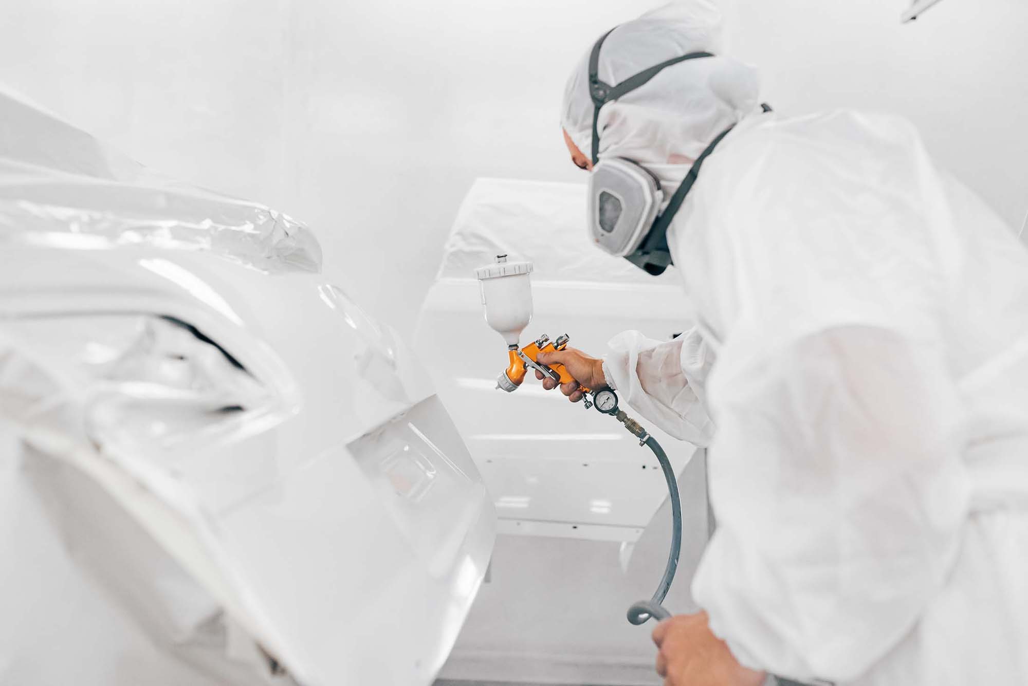 Painter in booth painting trunk white - auto paint repair - action colors