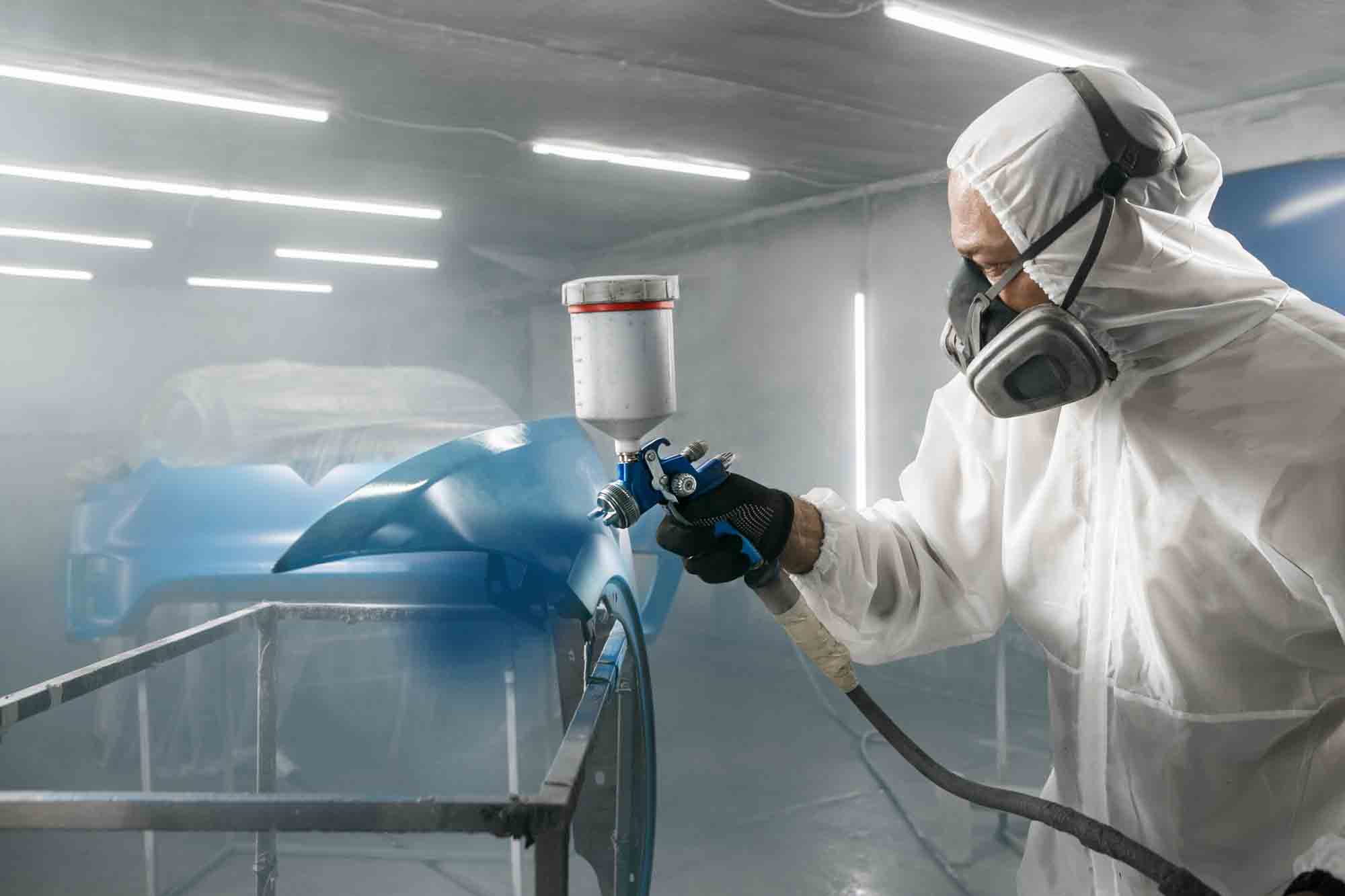 Painter spraying cars fender blue in booth - auto paint repair - action colors