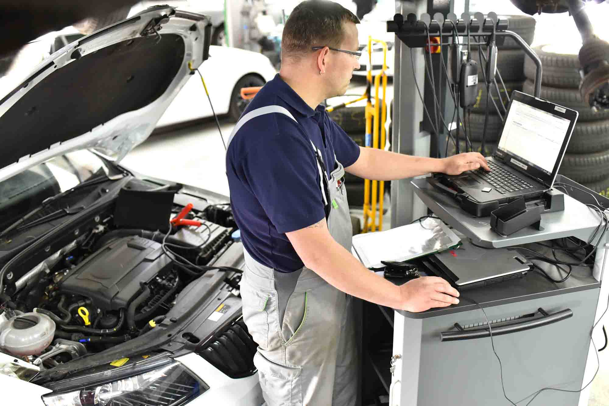 Technician running diagnostics on vehicle - action colors tallahassee florida