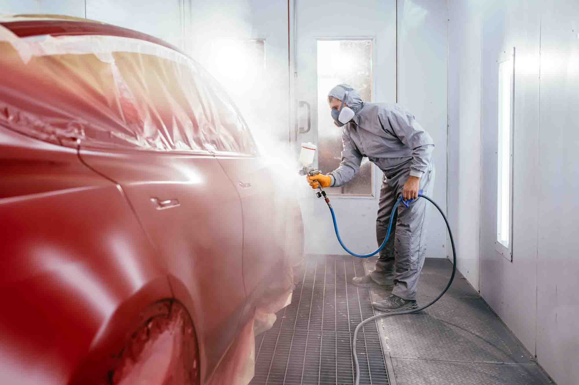 painter in booth spraying red suv - auto paint repair - action colors 