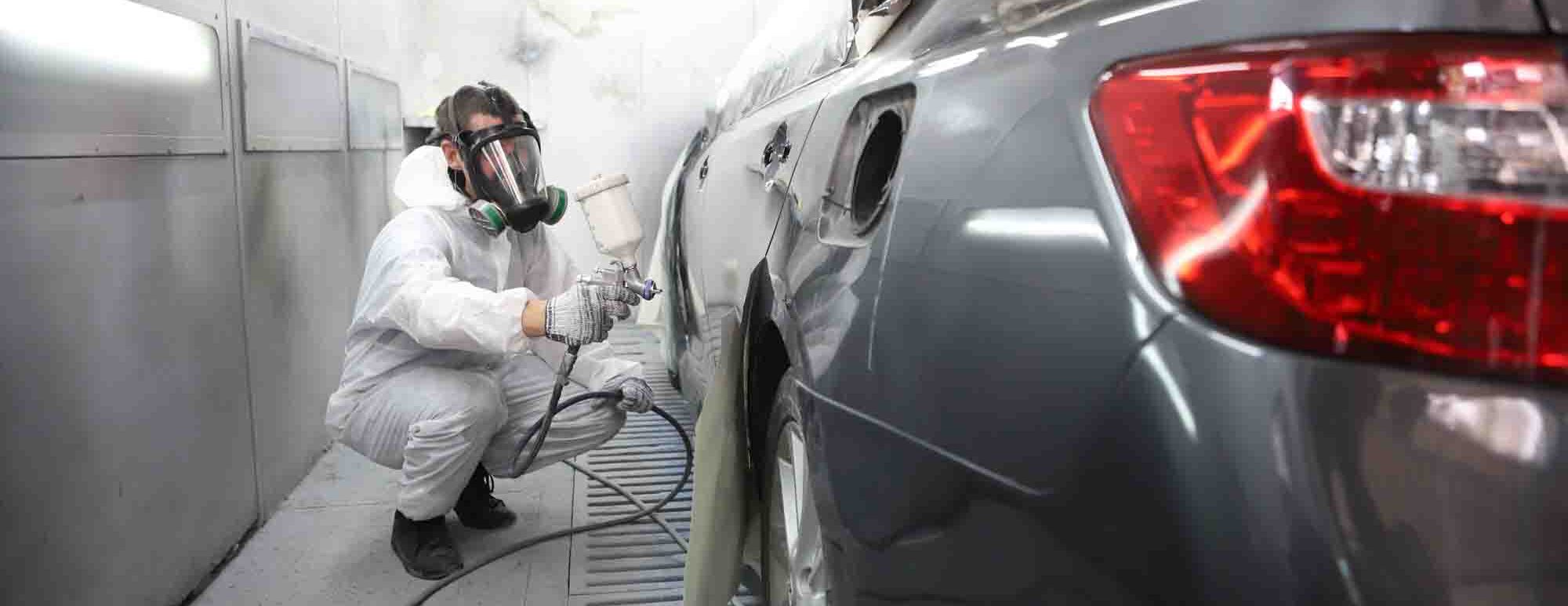 painter in booth spraying silver sedan - auto paint repair - action colors 